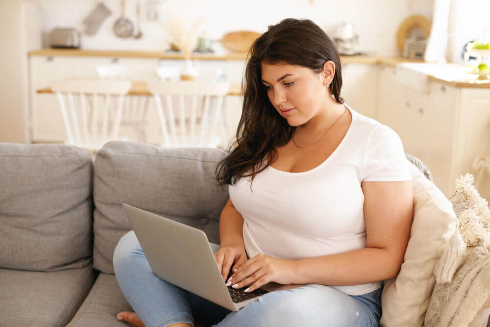 Woman on couching looking at laptop